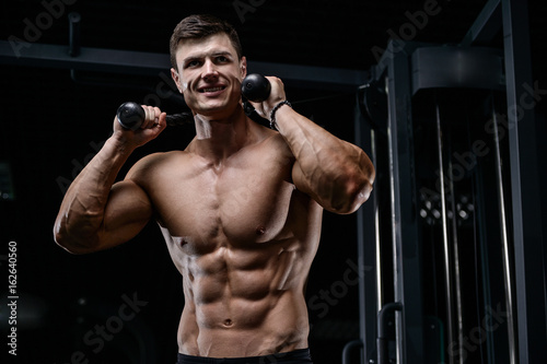 Muscular handsome athletic bodybuilder fitness model posing after exercises in gym on diet . © antondotsenko