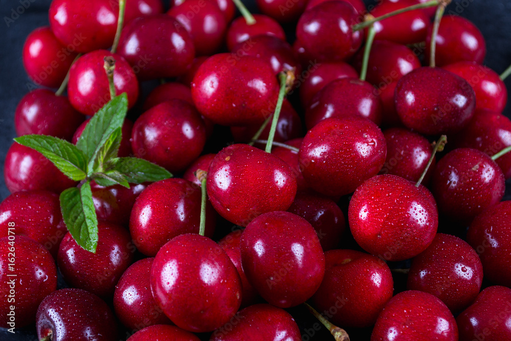 Sweet cherries With mint leaves as a background Sweet cherries With mint leaves as a background