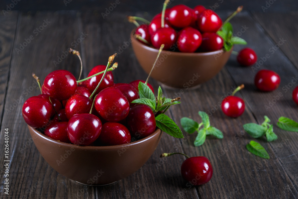 Fresh cherries in clay bowl on dark table Fresh cherries in clay bowl on dark table