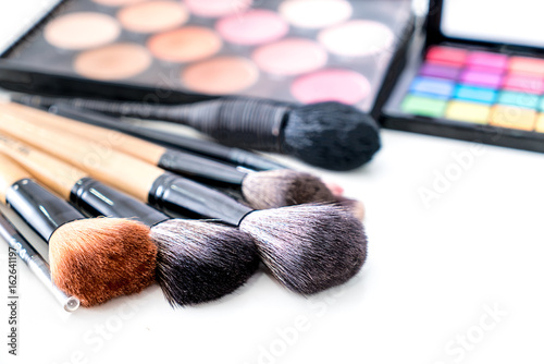 Various make up brush with make up products and concealers cosmetics on table in white background.