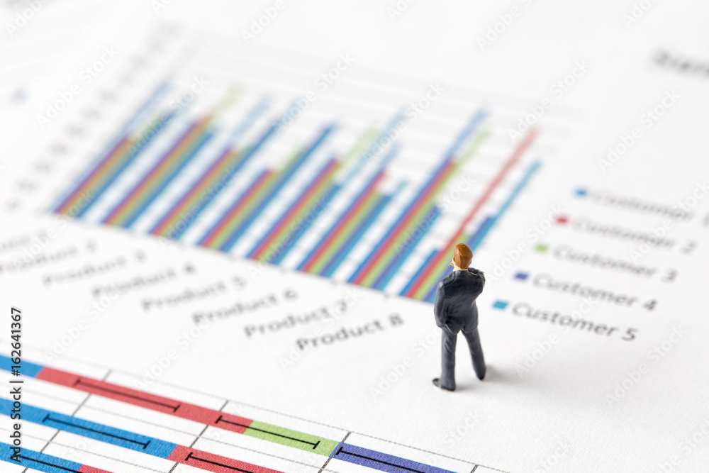 Miniature model group of businessman thinking with project for investment standing together on paper graph. Miniature model group of businessman thinking with project for investment standing together on paper graph.