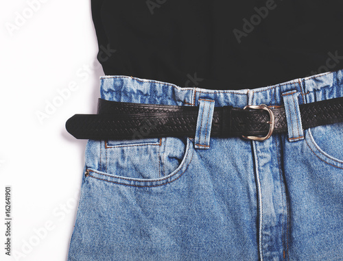 Closeup of blue vintage high-waisted mom jeans with black belt and black top isolated on white background. Flat lay.Top view. photo