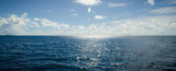 A panoramic scene of blue sky and the ocean with sunbeam shine above