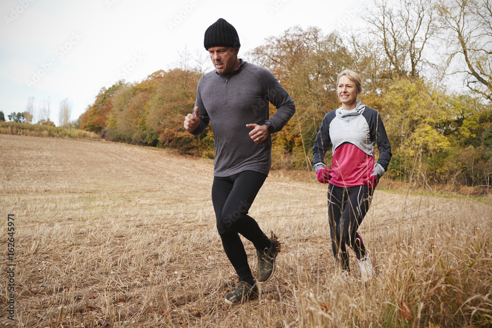 Mature Couple Running Around Autumn Field Together