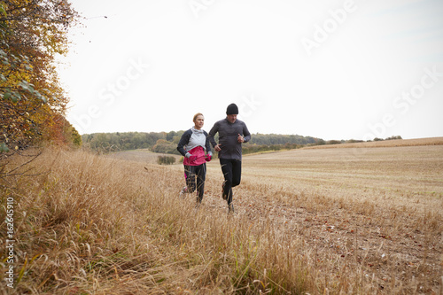Mature Couple Running Around Autumn Field Together © Monkey Business