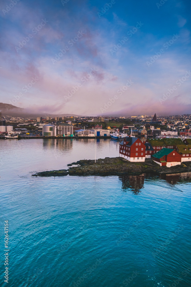 Aerial sunset view of Tórshavn, showcasing colorful architecture and serene coastline.