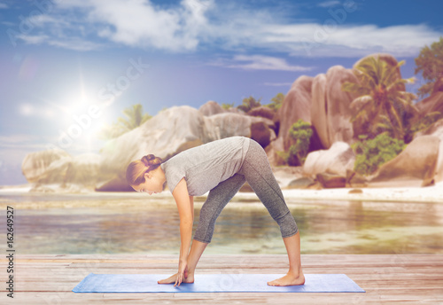 woman making yoga intense stretch pose on beach