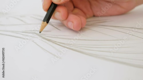 Designer draws a line on the paper. Hands drawing and paint. Female fashion designer drawing sketches in atelier. Close up