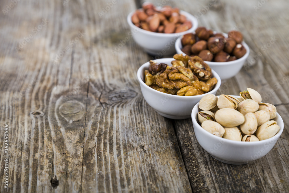Four bowls with nuts on a wooden table Four bowls with nuts on a wooden table