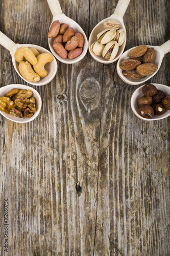 Nuts in a wooden spoons on a wooden table.