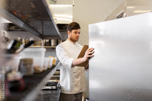 chef with clipboard doing inventory at kitchen