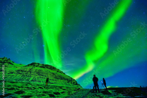 View of the northern light with photographers expecting near Kirkjufell Mountain in Iceland.