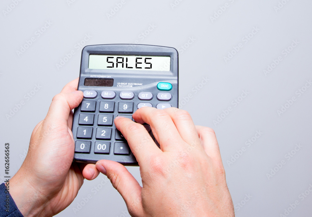 Businessman hands holding Calculator with SALES sign text message isolated on white Businessman hands holding Calculator with SALES sign text message isolated on white