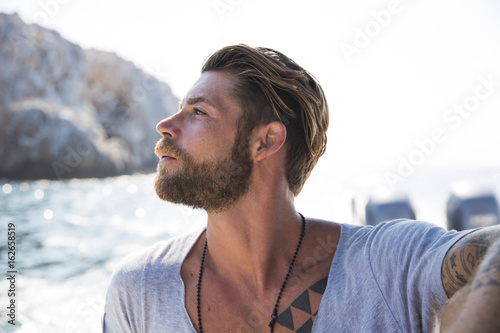 Stylish man with tattoos enjoing an ocean boat ride.