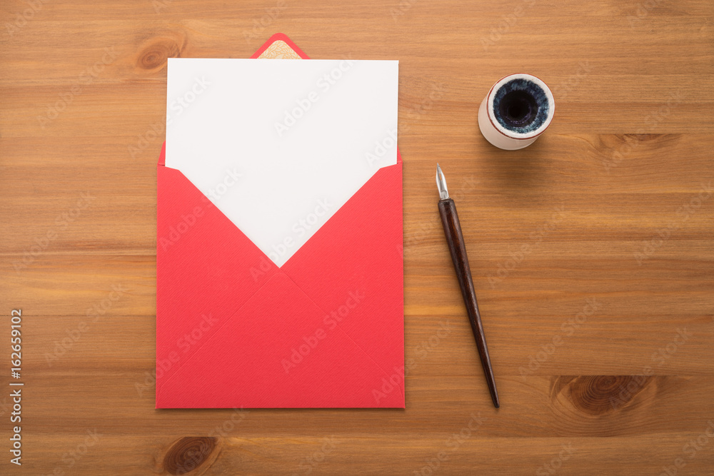Red envelope, ink pen, inkwell on a wood table Red envelope, ink pen, inkwell on a wood table