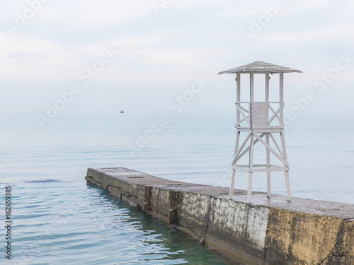 White wooden rescue tower on the breakwater. Seascape in soft blue tones