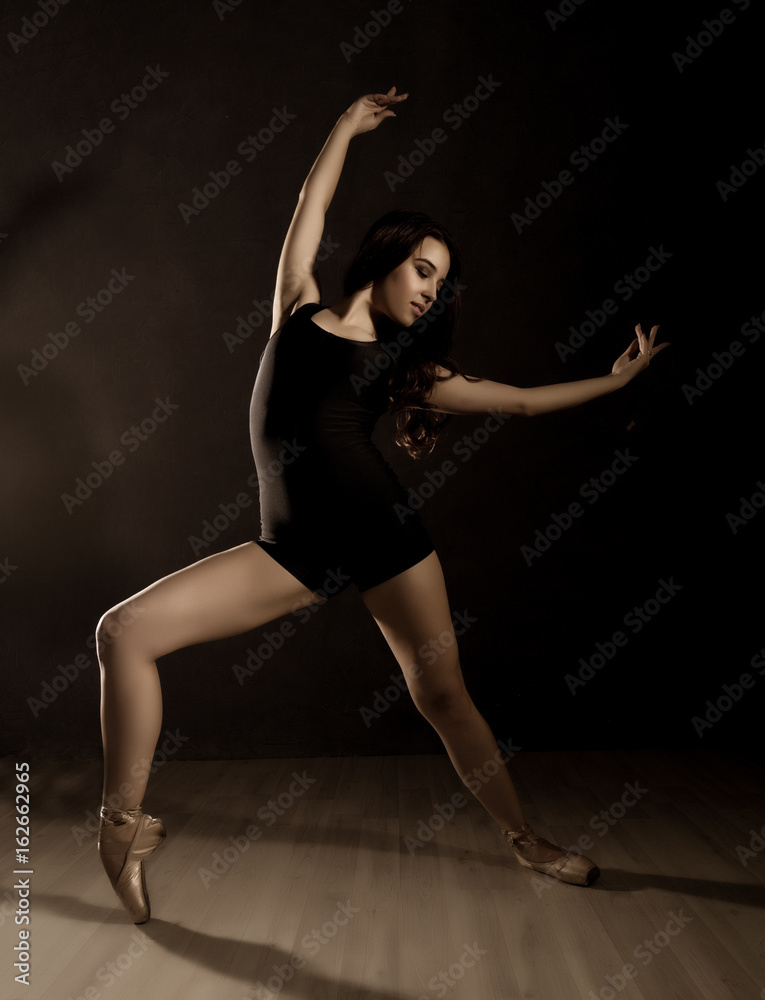 young beautiful ballet dancer in pointe shoes, dancing in a dark background