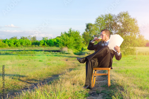 Business man in suit notes a successful contract on nature, bright summer photo.