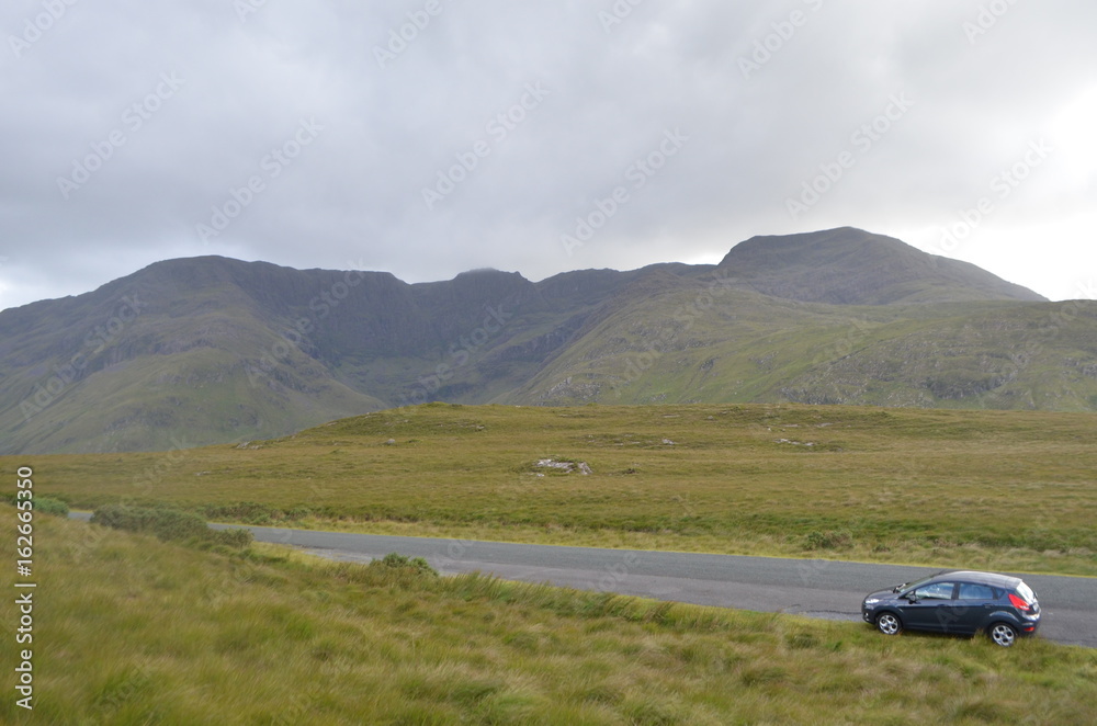 Car in the Middle of a National Road with Vegetation and Mountains in Ireland