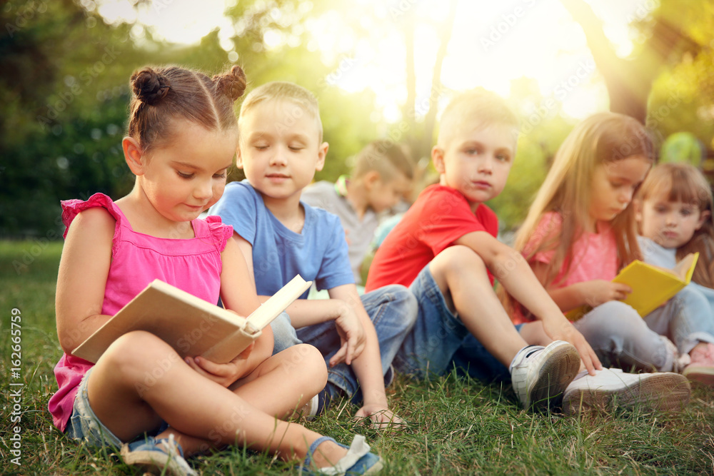 Group of happy kids reading books in park Group of happy kids reading books in park