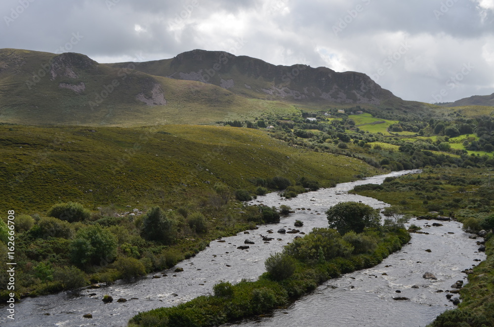 Small River Flow in Green Vegetation and Mountain Landscape in a National Road in Ireland