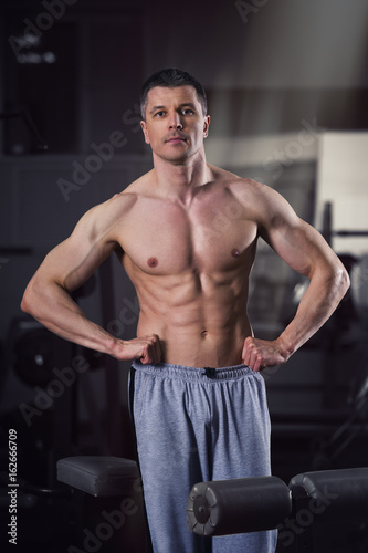 Handsome bodybuilder posing in gym, perfect muscular male body