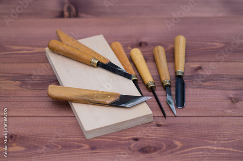 Tool kit for woodcarving. Knives for carving on wooden background