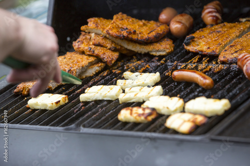 Caucasian man making food with a gas grill outdoors. Focus point on the food.