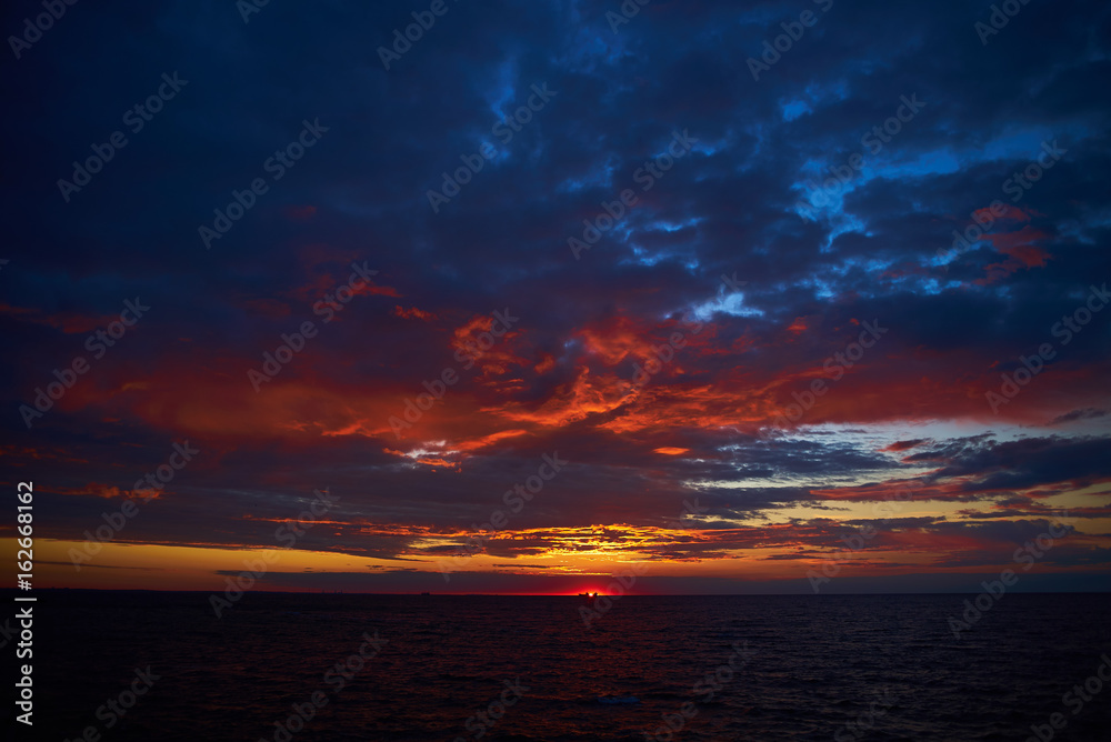 Amazing sunrise over dark sea with deep blue and red colors