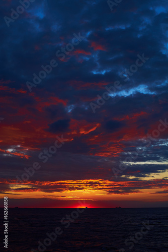 Amazing sunrise over dark sea with deep blue and red colors © Alexander Belinskiy