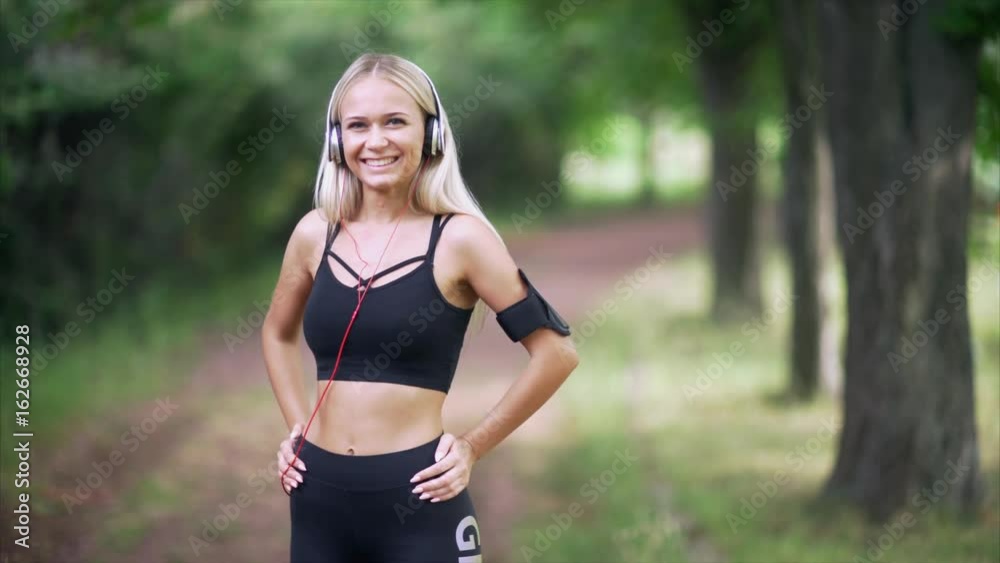 Portrait of a woman in headphones smiling against a background of green trees. Portrait of a woman in headphones smiling against a background of green trees.