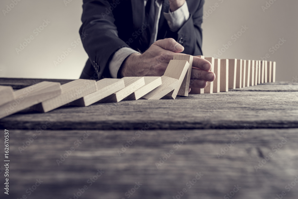 Toned image of a businessman stopping domino effect - obrazy, fototapety, plakaty 