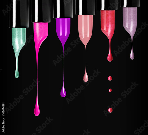 Melting colored lipsticks with falling drops down on black background