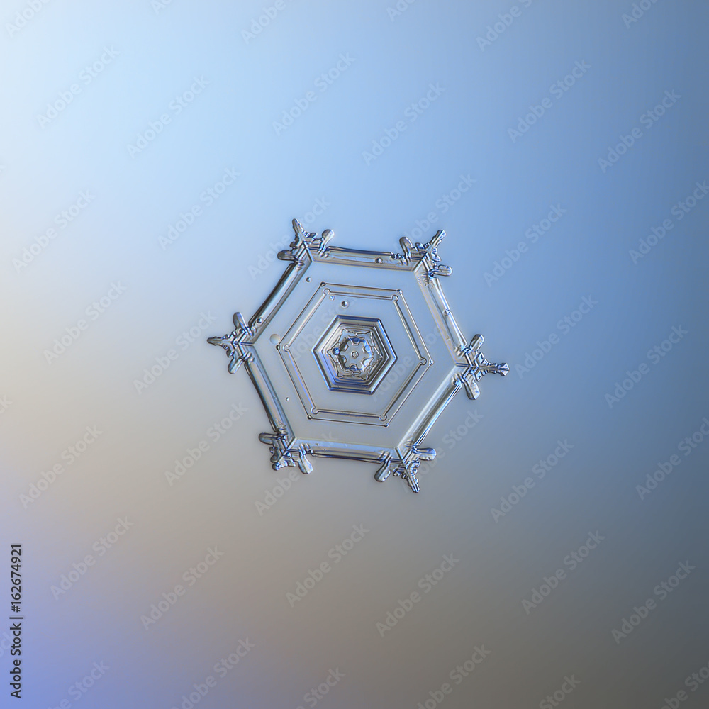 Snowflake glitter on smooth gradient background. Macro photo of real snow crystal: large star plate with six tiny arms and simple hexagonal shape with glossy, relief surface. 