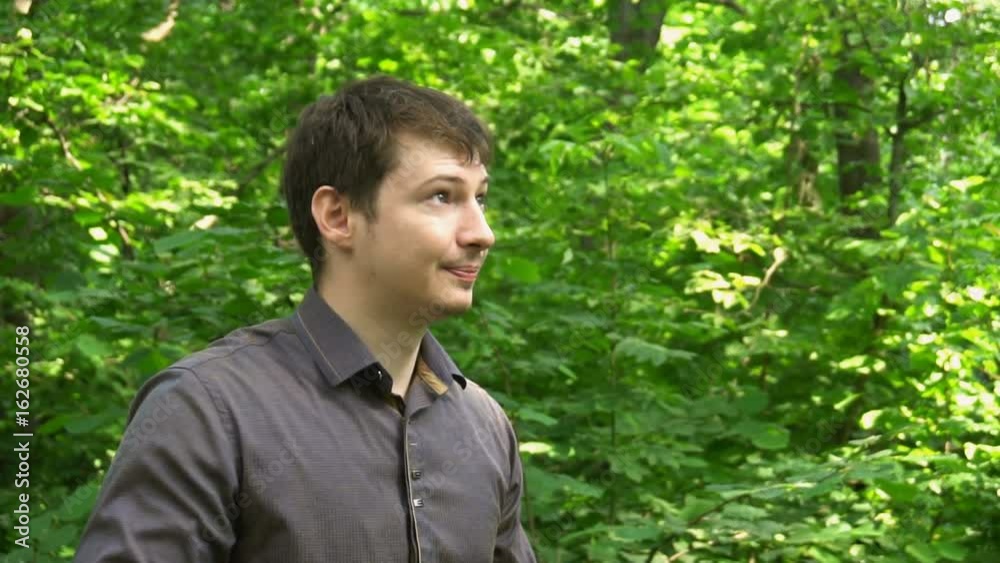 a young man stands in the woods,throws the jacket over his shoulder and makes a selfie. Slow motion. a young man stands in the woods,throws the jacket over his shoulder and makes a selfie. Slow motion.