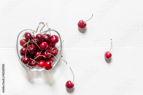 A lot of cherry in bowl on white background top view copyspace