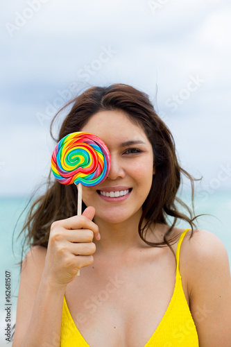 Happy young woman posing with lollipops at the beach in summertime © baconstudiony