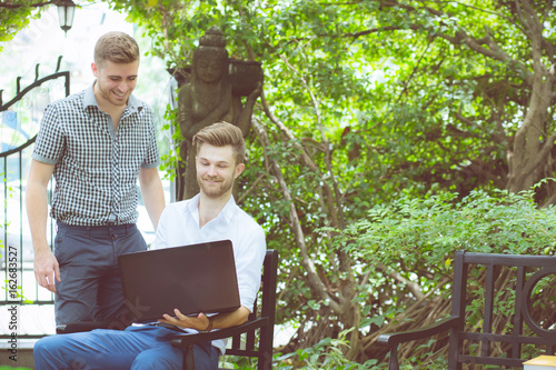 Two business people use of the notebook computer at outdoor.