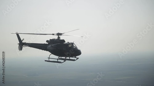 the helicopter flies high in the sky