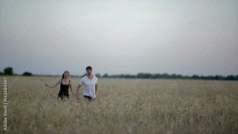Romantic Couple at Sunset. Two people in love at sunset or sunrise. Man and woman on field Romantic Couple at Sunset. Two people in love at sunset or sunrise. Man and woman on field