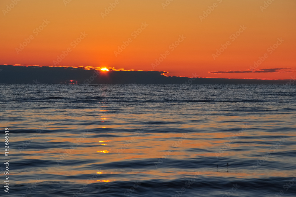 Dawn at the Ladoga. The sun rising above the lake reflecting in the waves