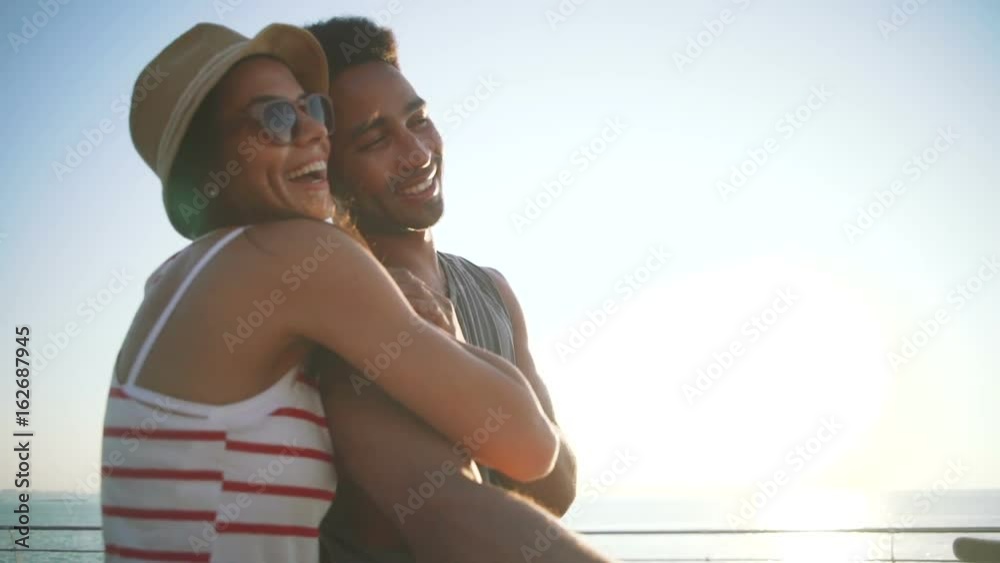Portrait of a mixed race couple on tandem bicycle outdoors near the sea, slow motion