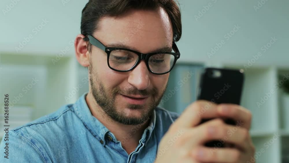 Portrait of happy business man using smart phone for chating with business partner in the office. Close up. Portrait of happy business man using smart phone for chating with business partner in the office. Close up.