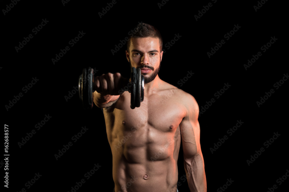 Model Exercising Shoulders With Dumbbells On Black Background