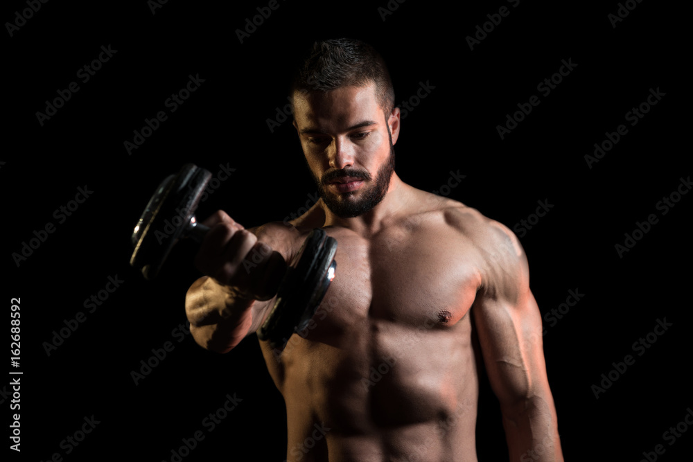 Model Exercising Shoulders With Dumbbells On Black Background