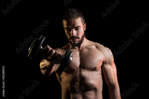 Model Exercising Shoulders With Dumbbells On Black Background © Jale Ibrak