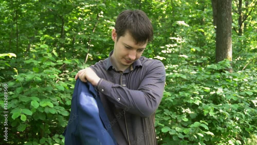 young businessman wearing a jacket standing in a forest. slow motion young businessman wearing a jacket standing in a forest. slow motion