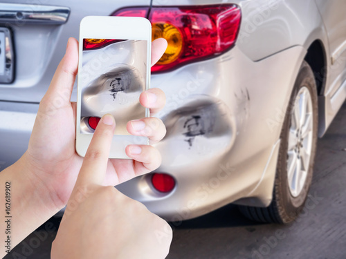 woman using mobile smartphone taking photo of car accident damaged for insurance