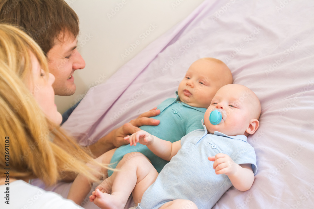 indoor portrait of young beautiful mother and father with baby, family with twins at home indoor portrait of young beautiful mother and father with baby, family with twins at home