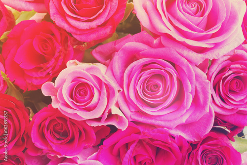 round bouquet of pink and magenta roses close up background, retro toned